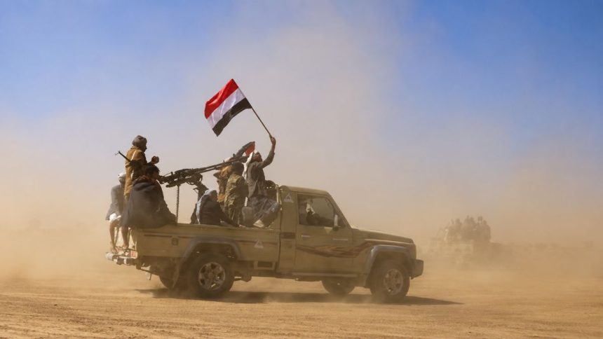Houthi fighters riding in a pickup truck with a Yemeni flag