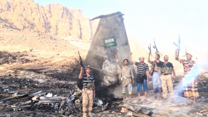Houthi fighters beside claimed wreckage of a Saudi F-15 in Yemen.