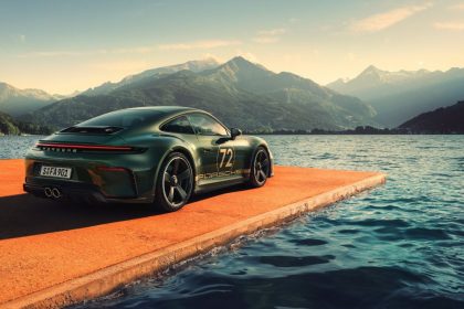 Porsche 911 GT3 on a lakeside pier with mountains in the background