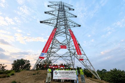 Workers pose beneath a 765 kV electricity transmission tower at the Dasu transmission line project in Pakistan.