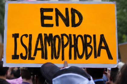 Protester holding an orange “End Islamophobia” sign at a demonstration.