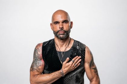 Gus Ormo in a black sleeveless vest posing for his AGAPE album promotional portrait.