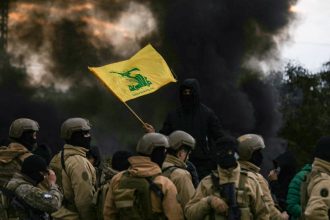Hezbollah supporter waving the group’s flag in front of Lebanese army troops during a protest in Beirut.