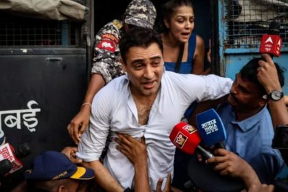 Indian actor Imran Khan emerges from a police van surrounded by police personnel and reporters following his arrest.