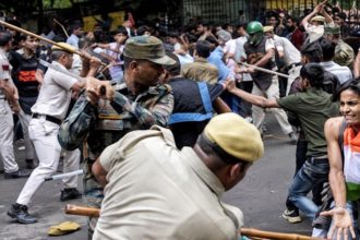 Delhi police officers wield batons as protesters confront security personnel during a street demonstration in India.