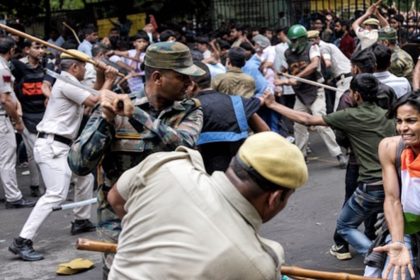 Delhi police officers wield batons as protesters confront security personnel during a street demonstration in India.
