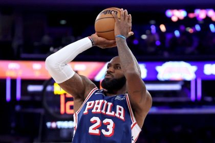 LeBron James shoots a basketball in a blue Philadelphia 76ers No. 23 jersey during a game.