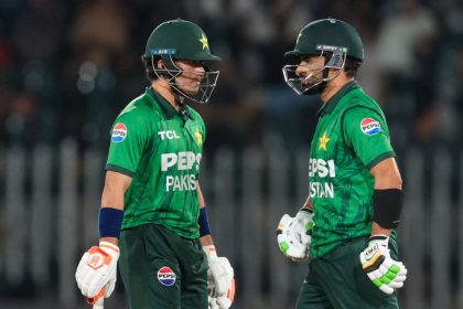 Two Pakistan cricket batsmen in green national team uniforms and helmets talk during the second T20 International against Sri Lanka at Rawalpindi Cricket Stadium.
