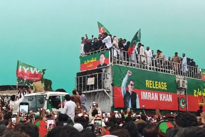 PTI supporters gather around a truck displaying a “Release Imran Khan” banner during a rally.
