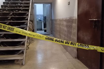 Yellow crime scene tape across a building corridor in connection with the reported deaths of a Karachi police officer’s family in Bin Qasim.