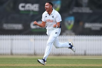 Australia's Scott Boland celebrates with clenched fists while wearing his white cricket uniform.