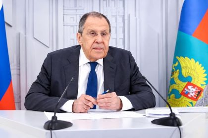 Russia's Foreign Minister Sergey Lavrov seated at a desk with microphones and documents.