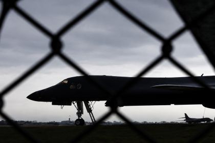A U.S. military bomber sits on the runway behind a security fence at an air base.