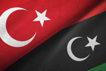 Turkish and Libyan flags featuring white crescents and stars on red and black backgrounds.