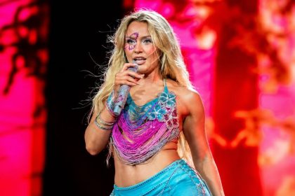 Zara Larsson singing into a microphone during a live concert.